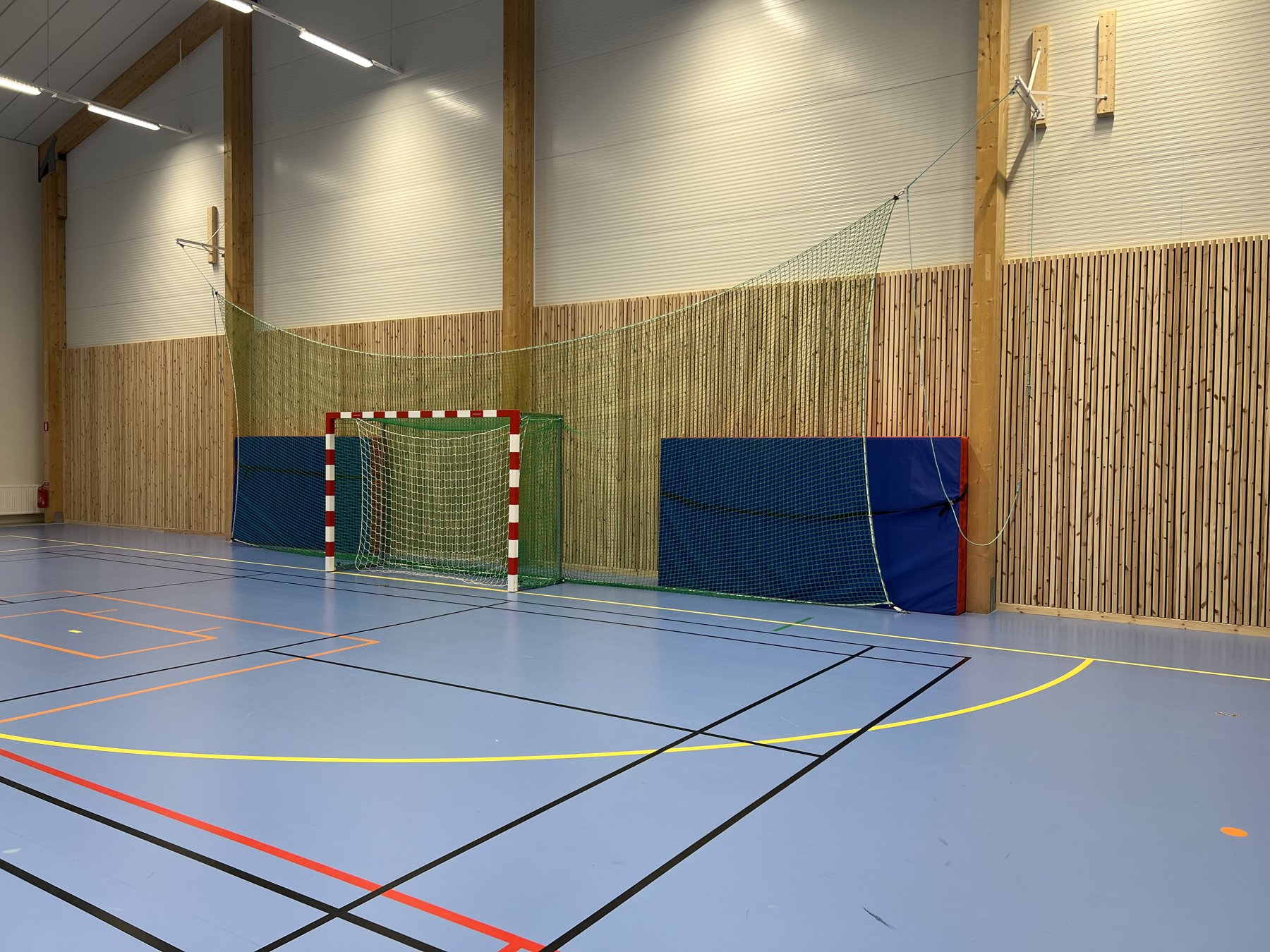 Nylagt sportgolv i en idrottshall med träpanel på väggarna
